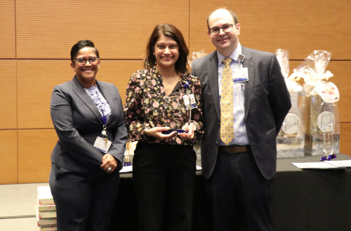 Leaders pose with team member holding an award.