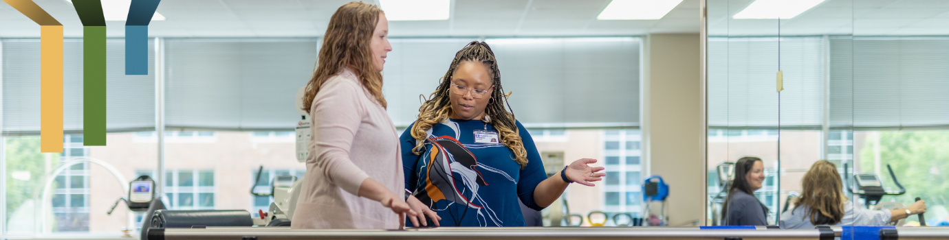 Female team member helps a patient walk.
