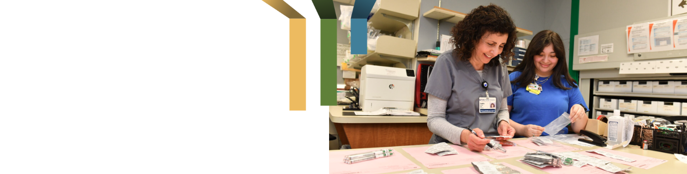 Two female pharmacy team members fill prescriptions together.