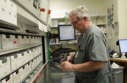 Male team member scans in pills at a hospital pharmacy.