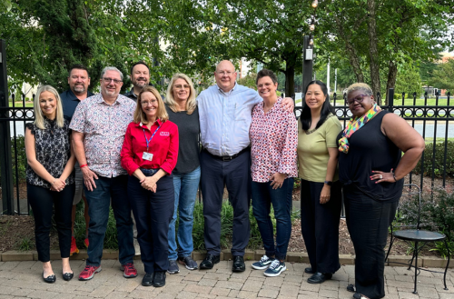 Group of team members smile together in outdoor setting. 