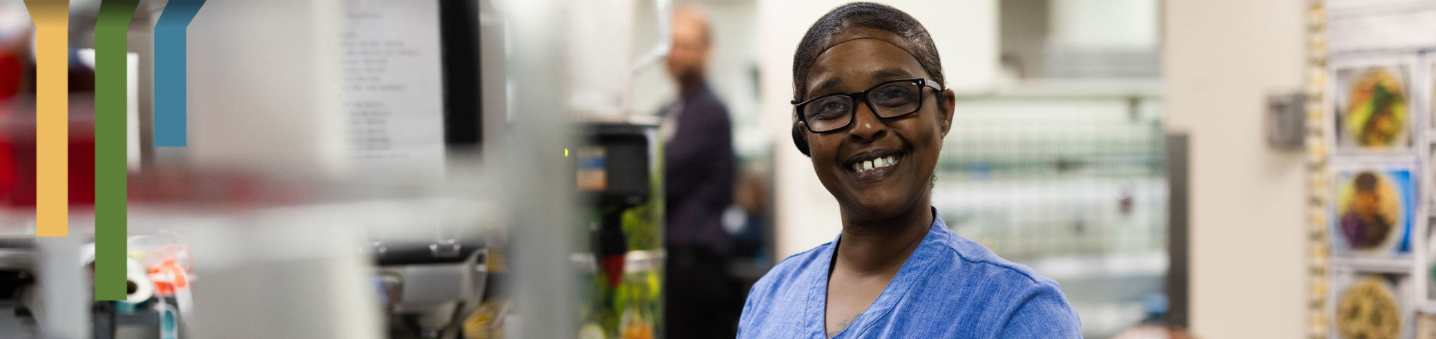 female team member smiling while prepping food at a hospital.