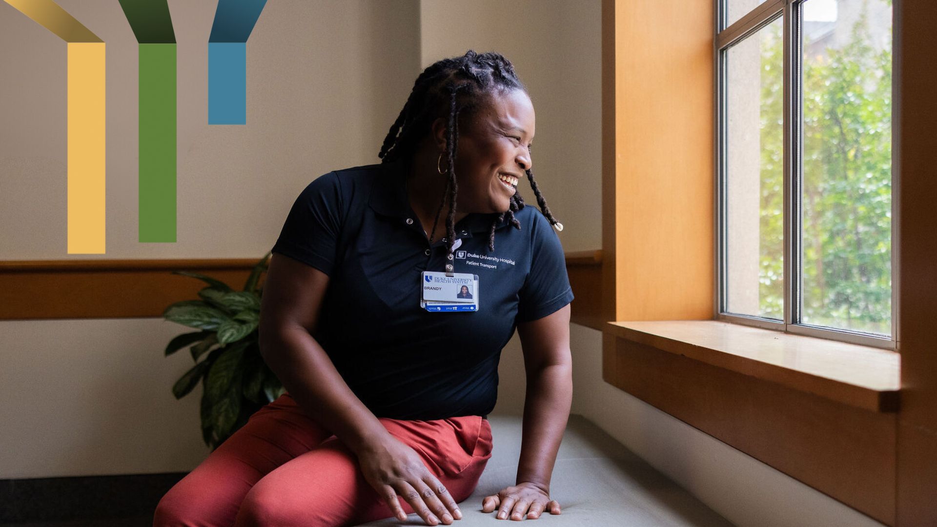 Female team member smiles while looking through a window on the Duke campus.