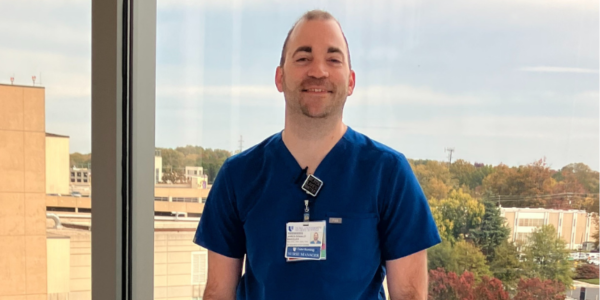 JD smiles in blue scrubs.