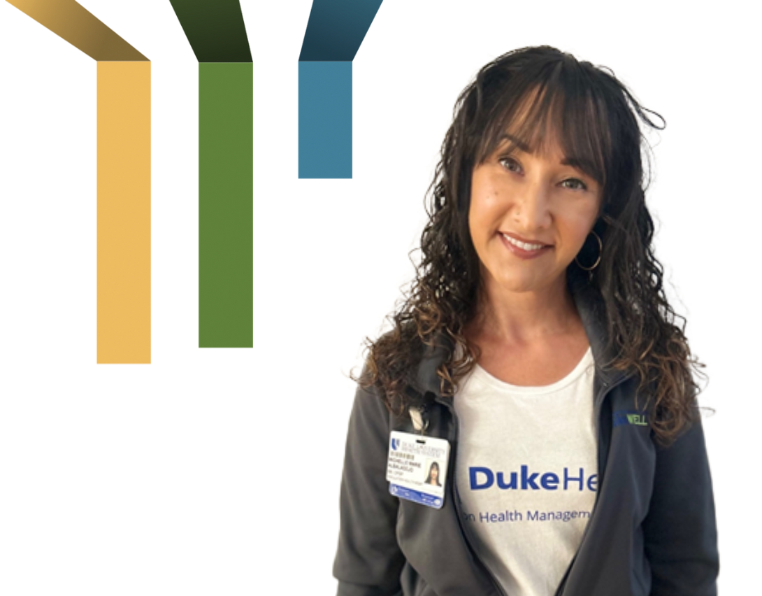 Two women smile while holding up two blue Duke Primary Care t-shirts.