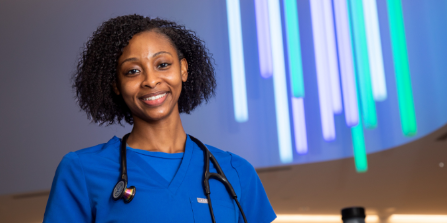 Nurse smiling in blue scrubs with stethoscope around her neck.