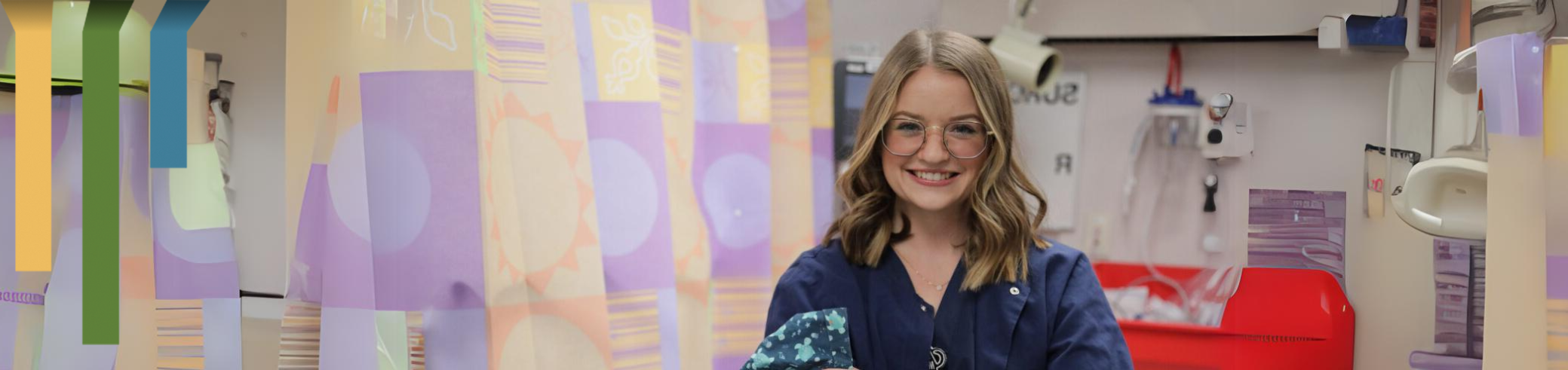 Female team member smiles in OR prep room with scrub cap.