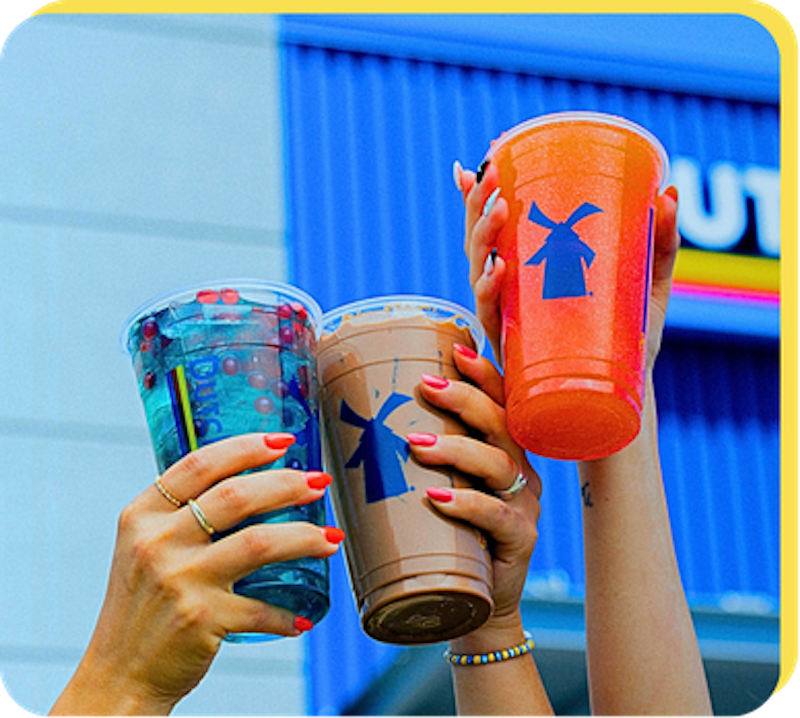 Three people holding up Dutch Bros drinks