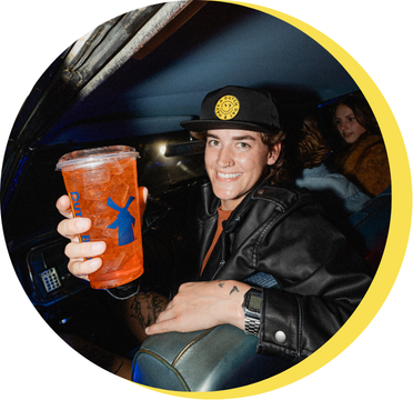 Person sitting on a bus with a red dutch bros drink in their hand