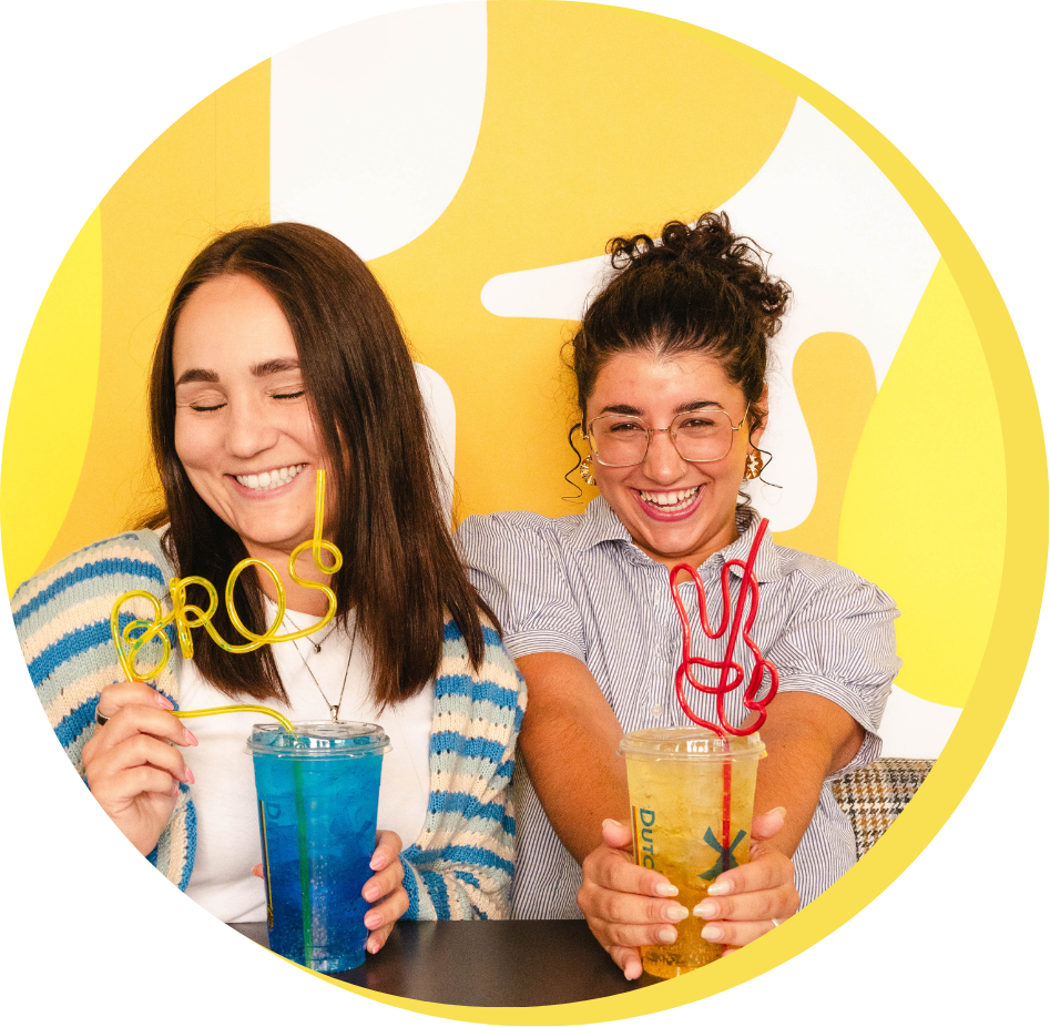 Two girls drinking dutch drinks out of a bendie straw