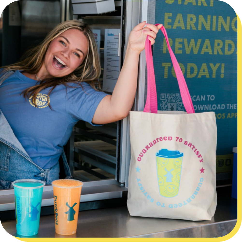 Brosita posing with two drinks holding a guaranteed to satisfy bag