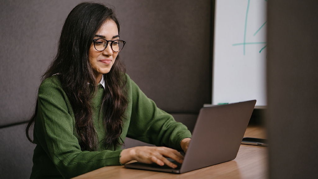 Frau arbeitet konzentriert an Laptop.