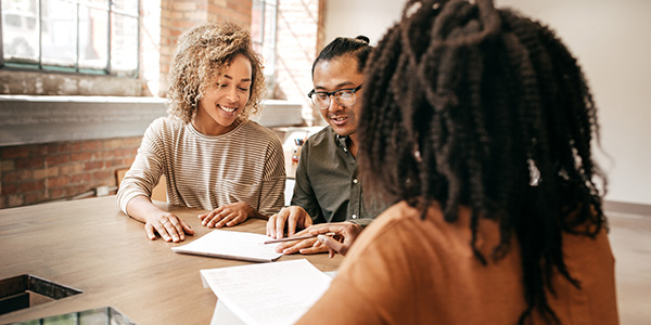 Three young professionals gathered around a table.