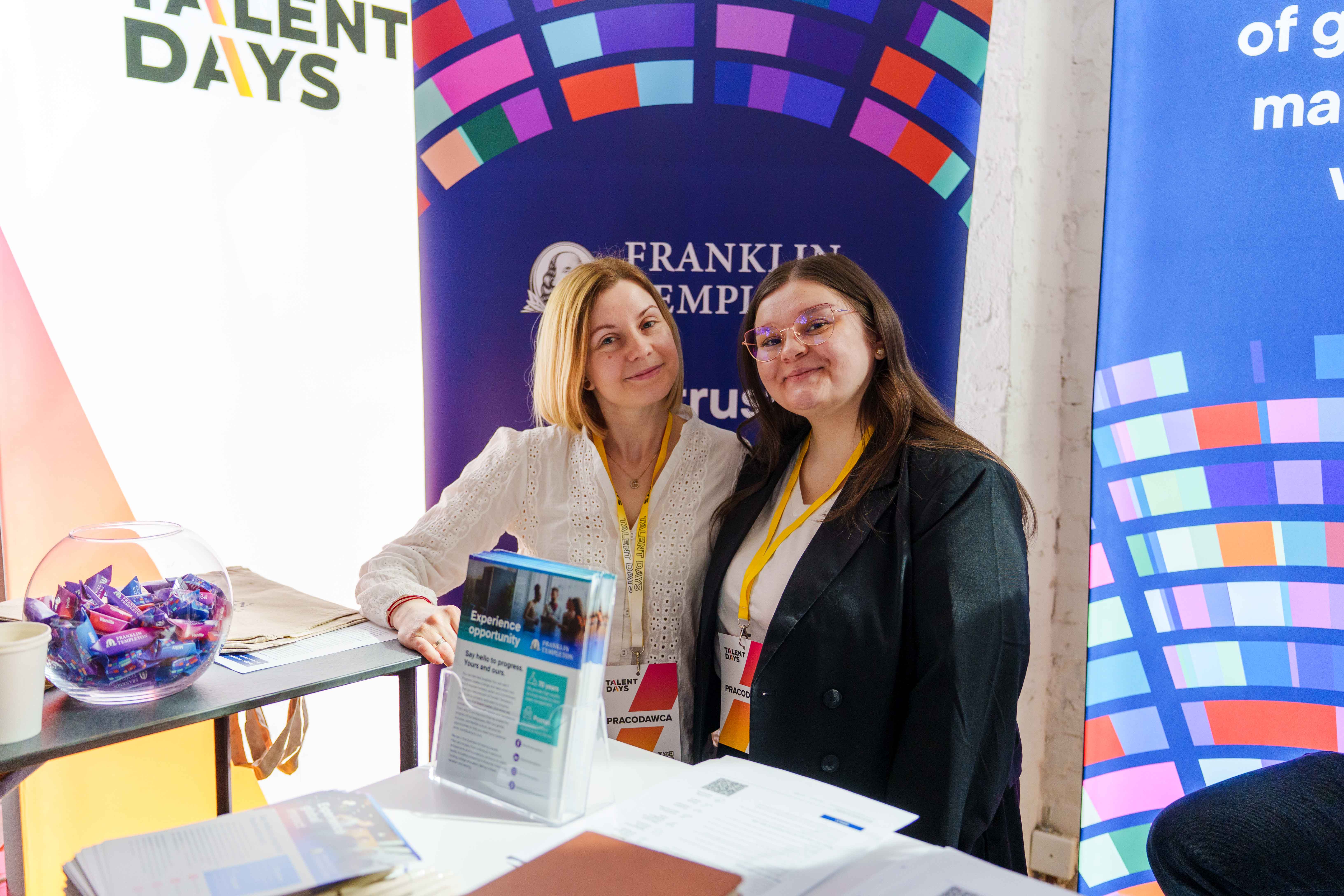Two smiling women stand behind a promotional table at a Franklin Templeton at Talent Days career event.
