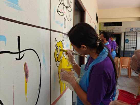A woman paints a mural on a white wall, adding details to a yellow lion.