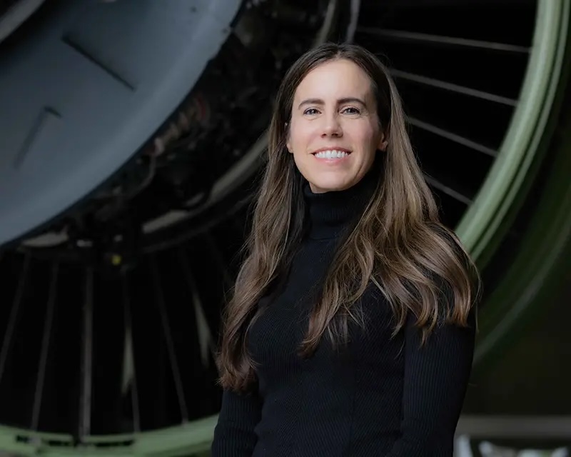 Woman in front of airplane engine smiling