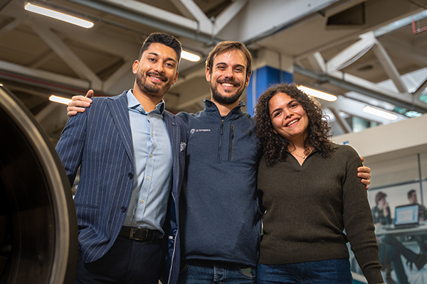 Three people smiling at camera with arms around each other.