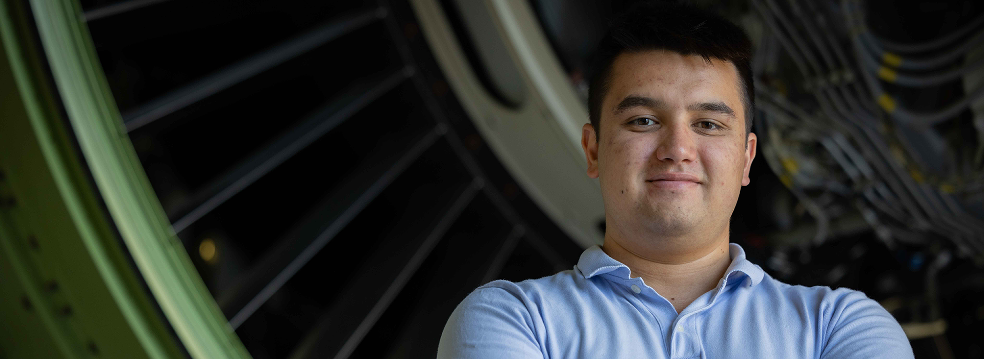 Young man standing in front of large jet engine.