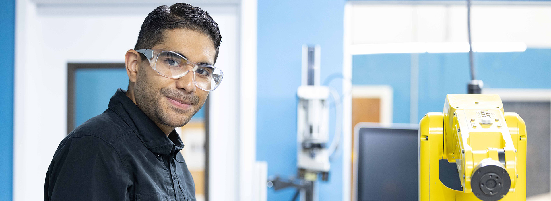 Young man standing next to automation machine