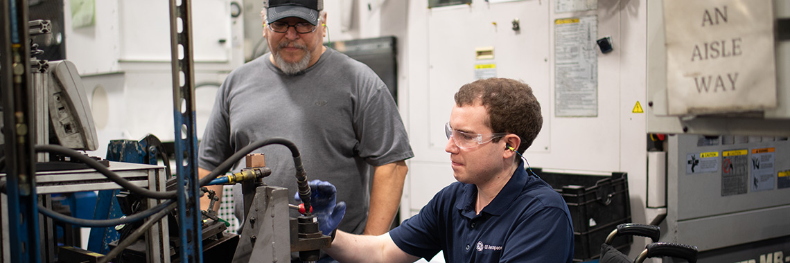 Two men working on manufacturing equipment