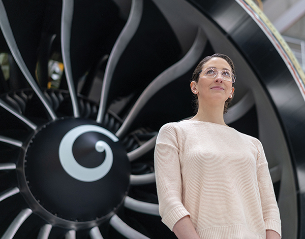 Woman standing in front of an airplane engine.