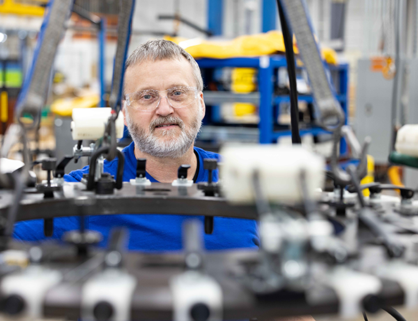Man in blue shirt looking through engine components. 