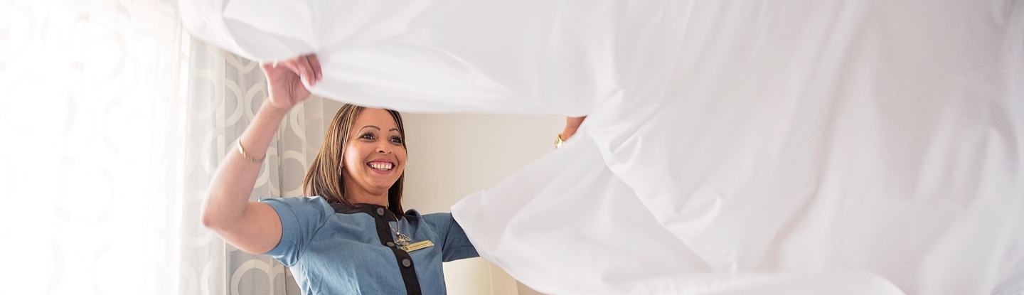 Team Member in housekeeping making a bed at a hotel
