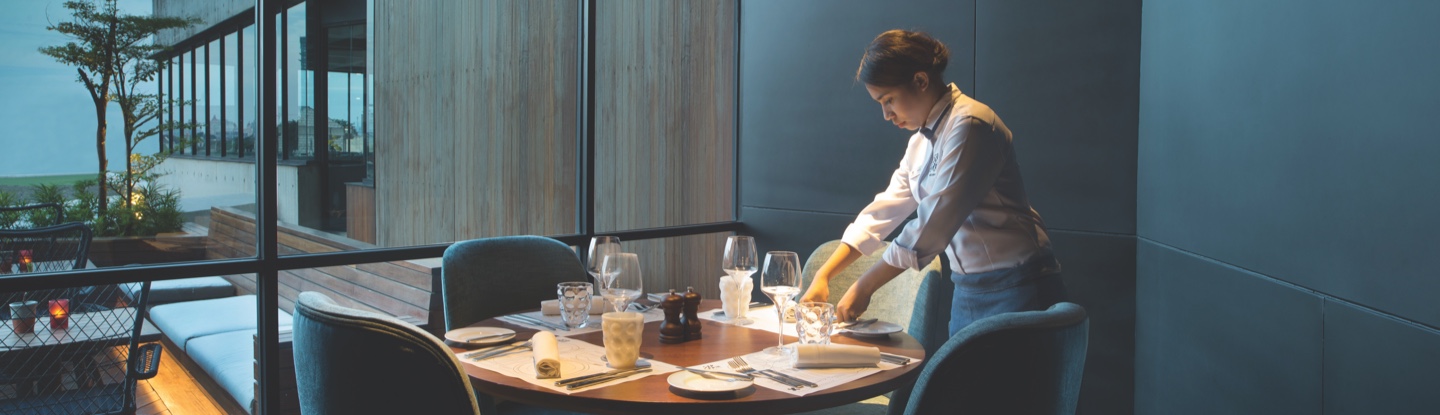 Food and Beverage Team Member setting a table in a hotel restaurant