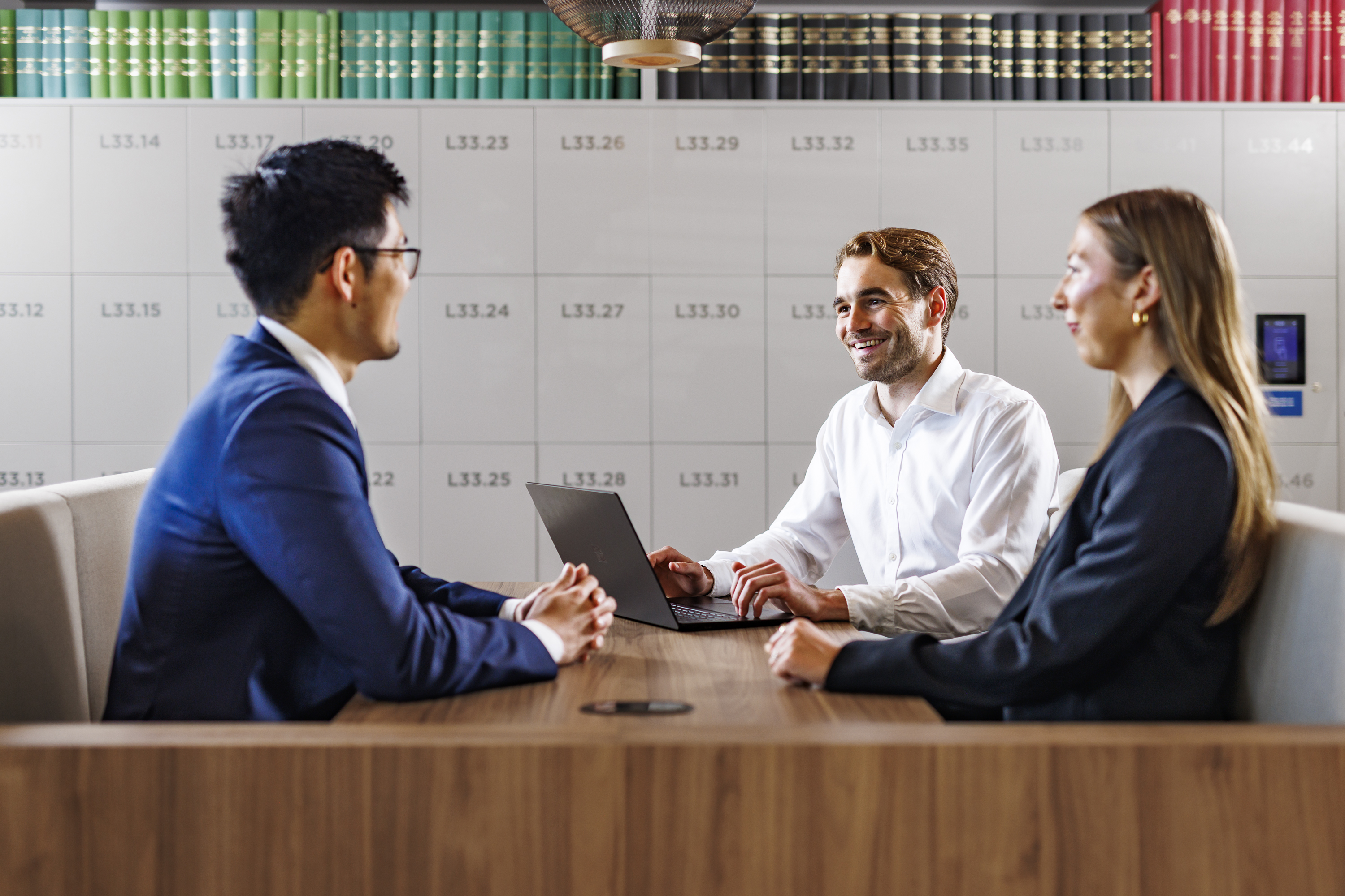 Three individuals chatting and working in a booth