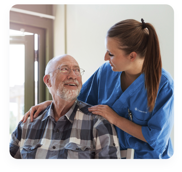 A CenterWell clinician embraces a male patient sitting in a chair at a Senior Primary Care center.