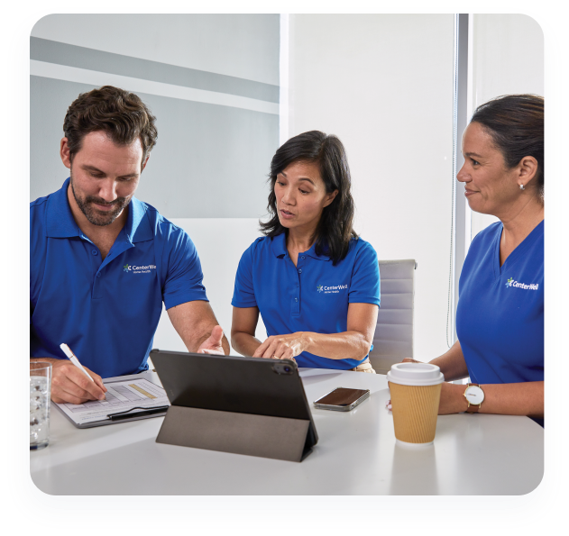 Three CenterWell Home Health clinicians sitting at a table discussing the plan of care for their patients.