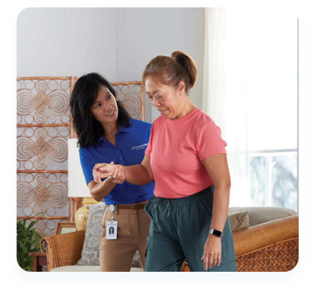 A CenterWell home Health Physical therapist working with a woman helping her walk in her house.