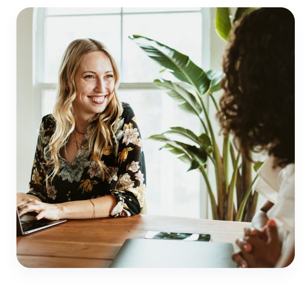 Two business women sitting at a table having a cheerful discussion.