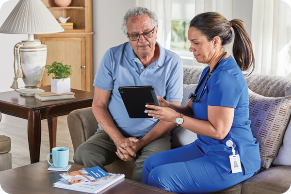 Home health nurse sitting on a couch talking with a man patient about his condition.