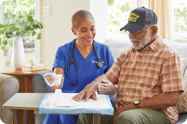 Home health nurse sitting on a couch talking with a man patient about his condition.