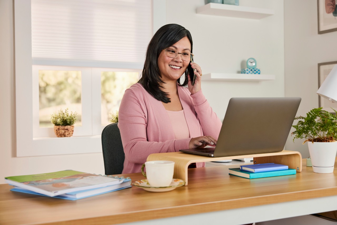 Woman working at home on laptop while on phone