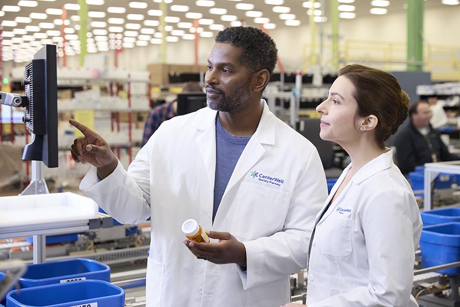 Male pharmacist showing female pharmacist something on a computer screen