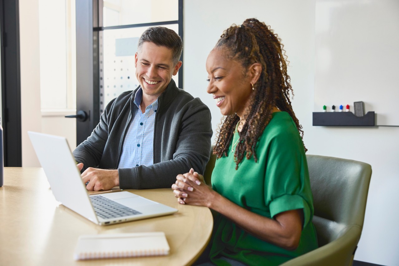 Coworkers collaborating and socializing while working on a laptop in an office