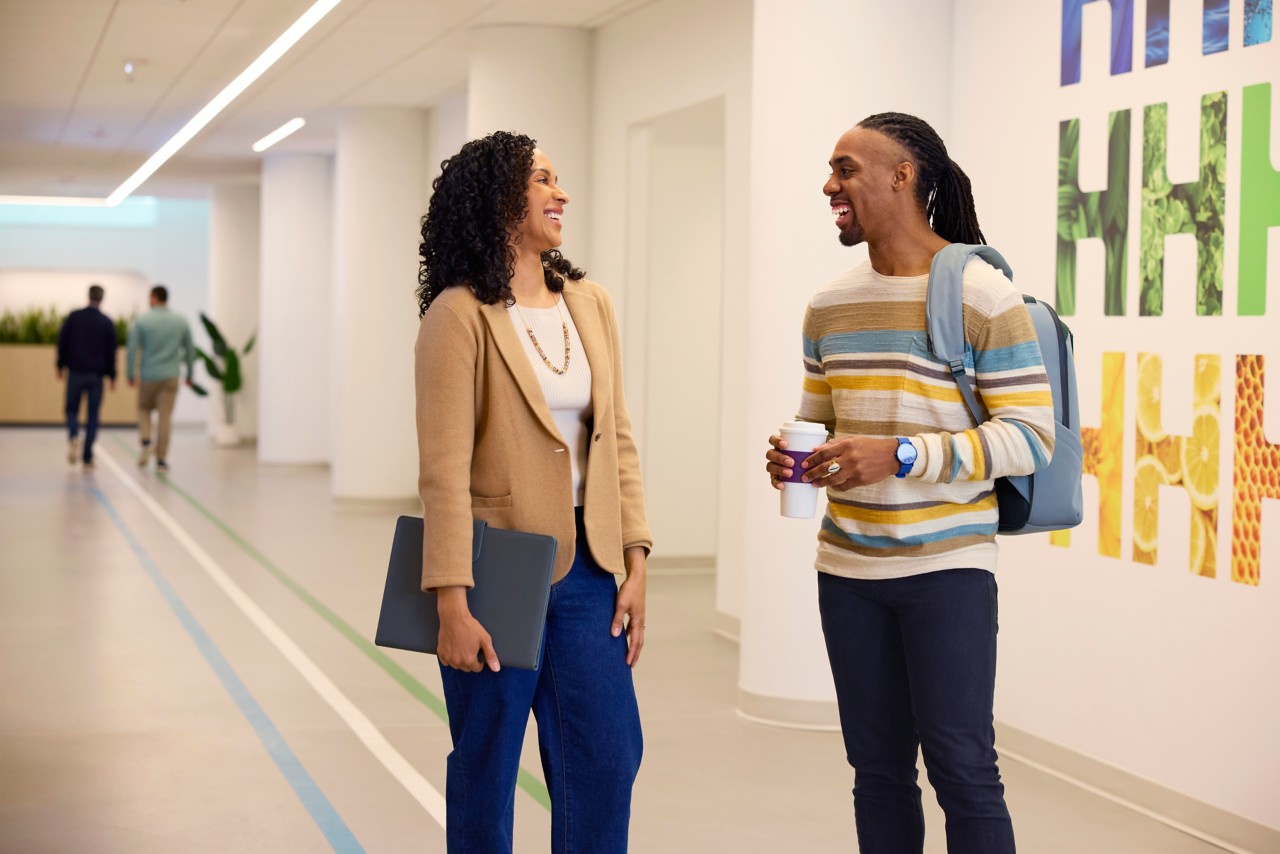 Man and Woman coworkers walking and socializing in office hallway