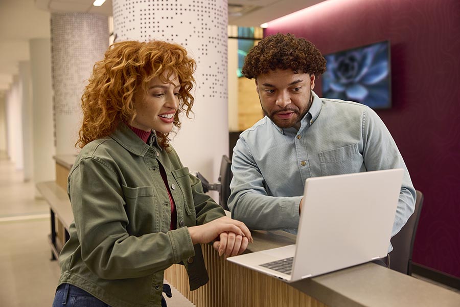 Male and female colleagues standing and collaborating on a laptop