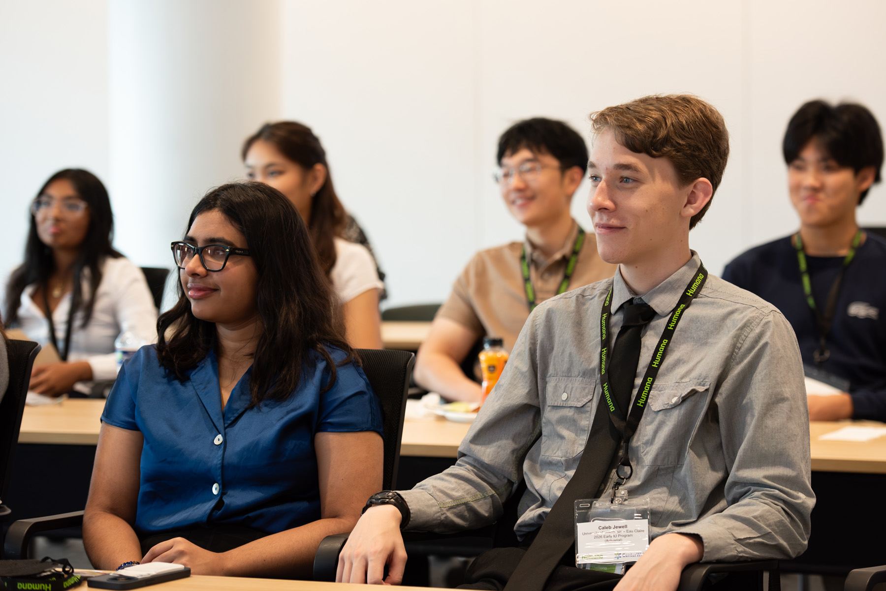 Group of Humana interns sitting in conference room listening to speaker and smiling