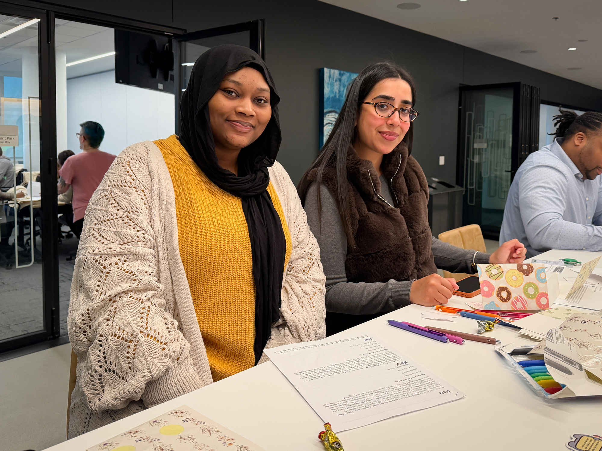 Two female students sitting at table studying looking up and smiling