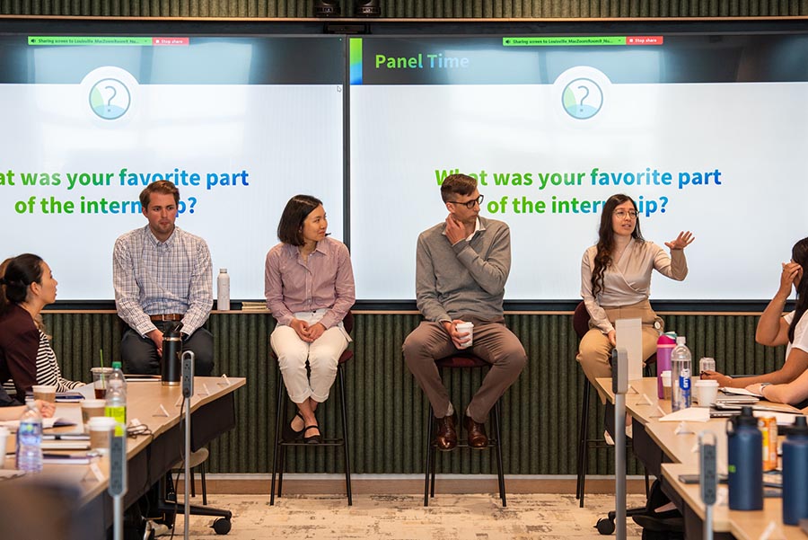 Four Humana Student Alumni sit on a panel in front of classroom of students answering questions