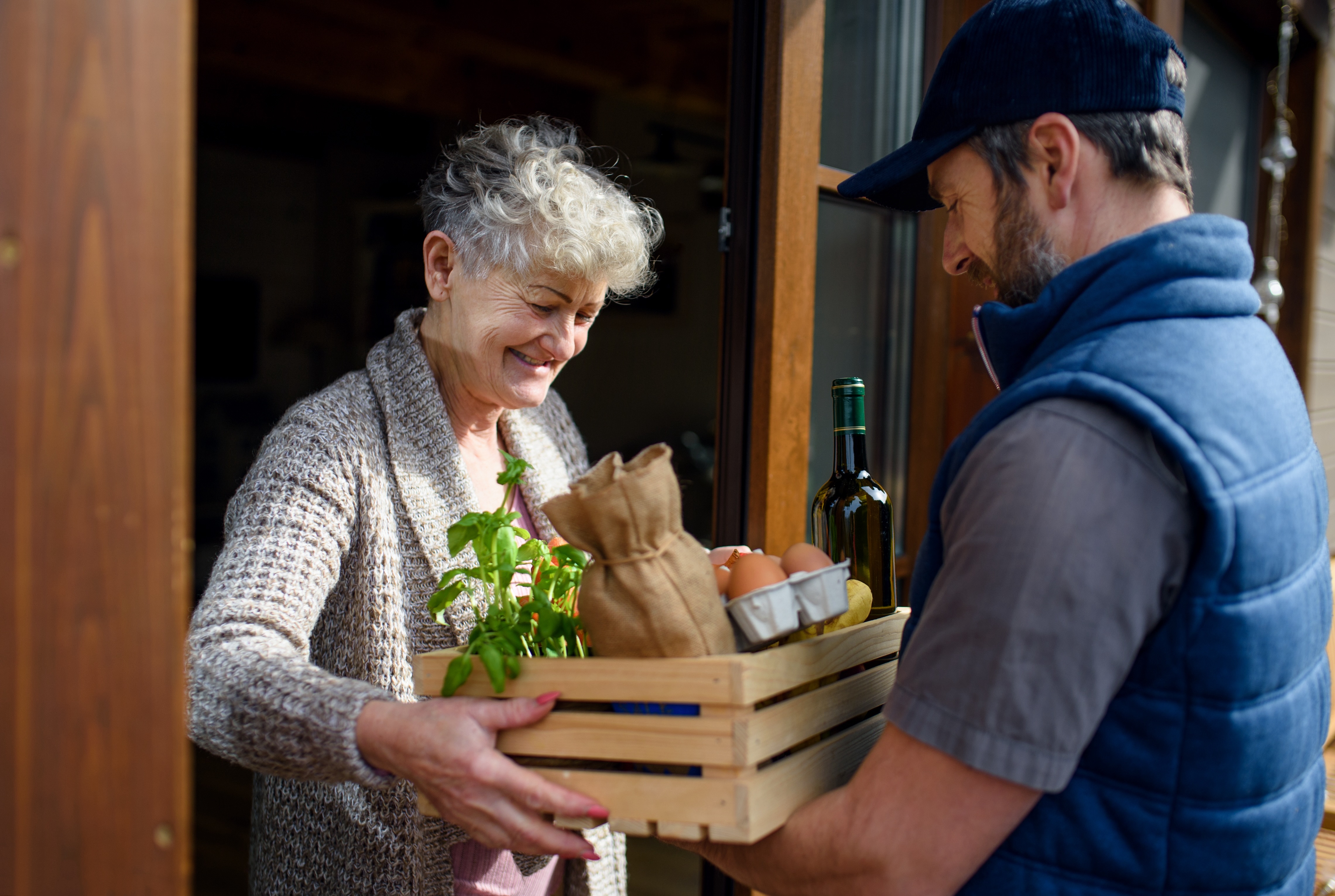 A man delivers groceries to an older woman