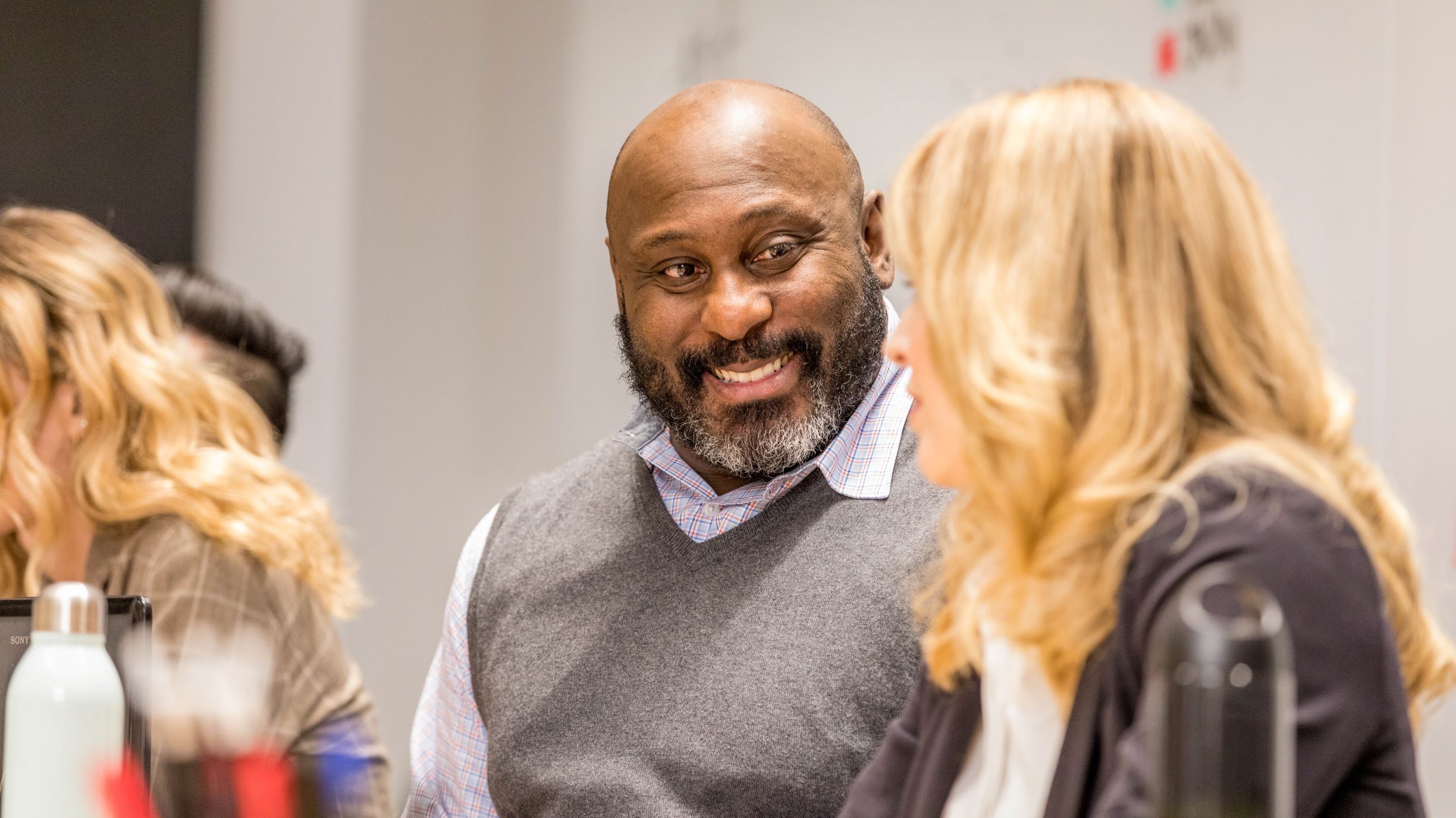 A male smiles while collaborating with female in an office