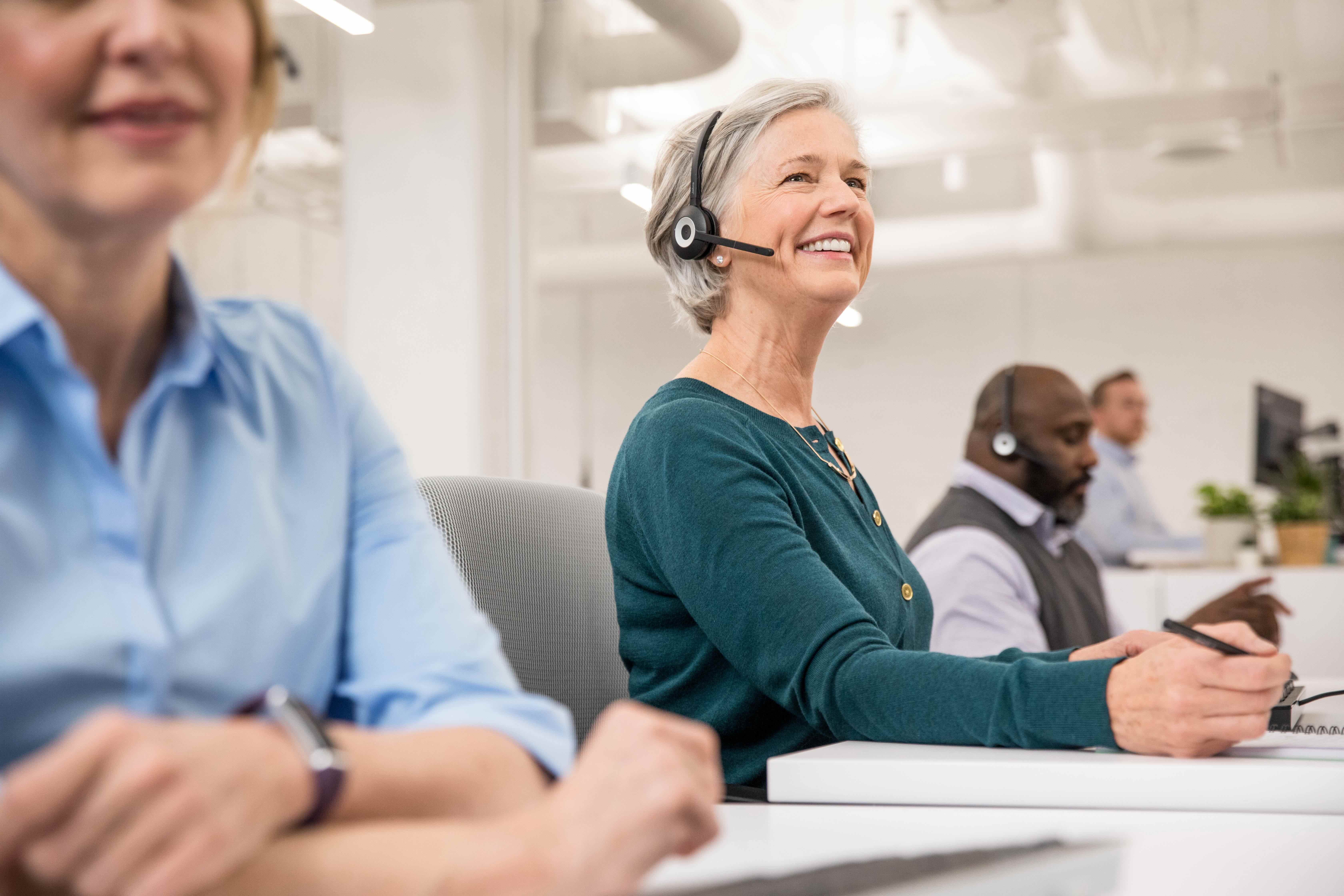 A group of professionals wearing headsets and working at computers in an office.