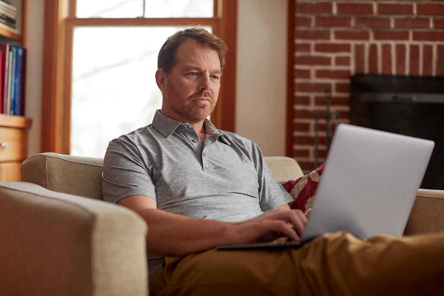 Male relaxing on couch with computer in lap and typing