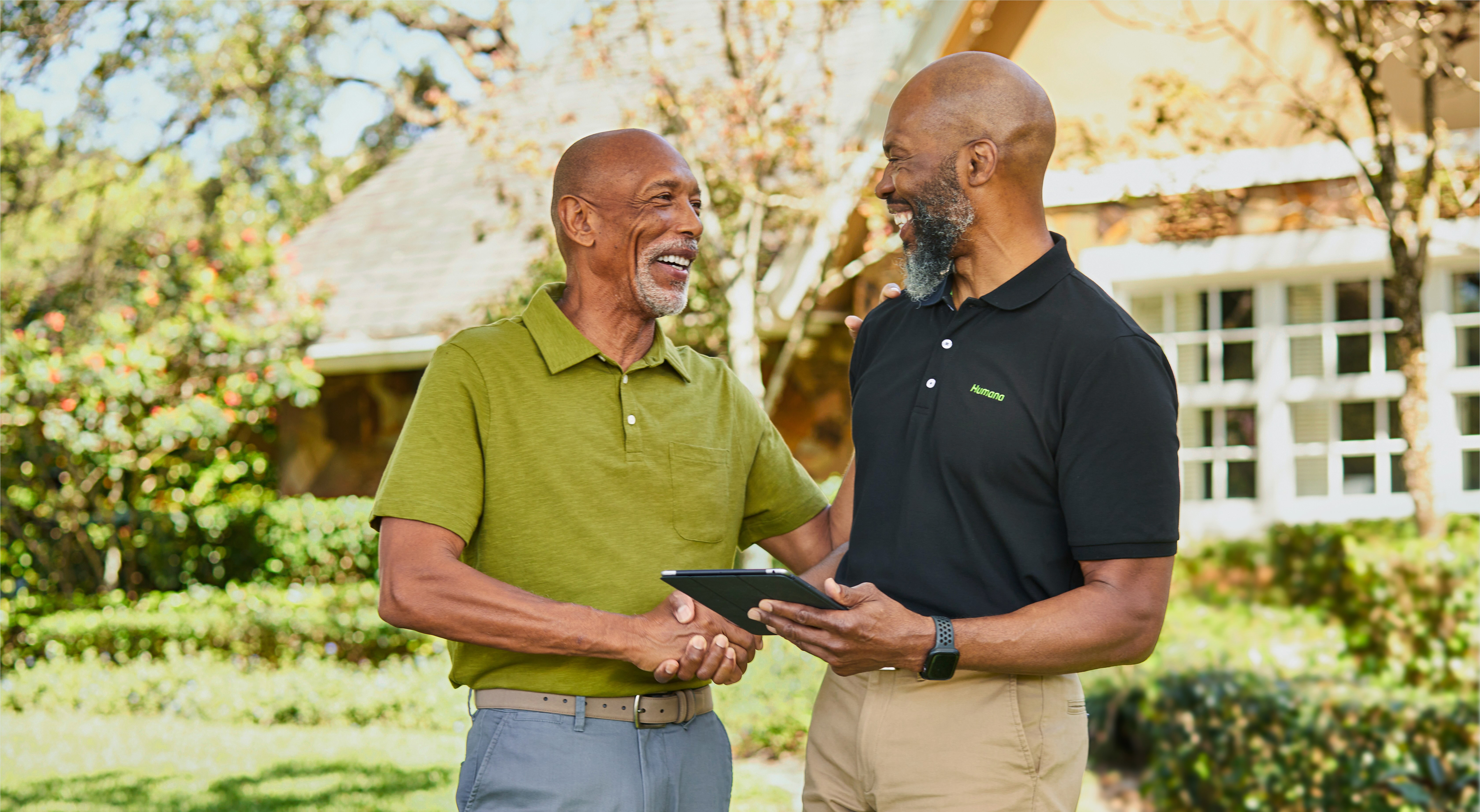 A senior man greeting a male Humana agent in front of a house.