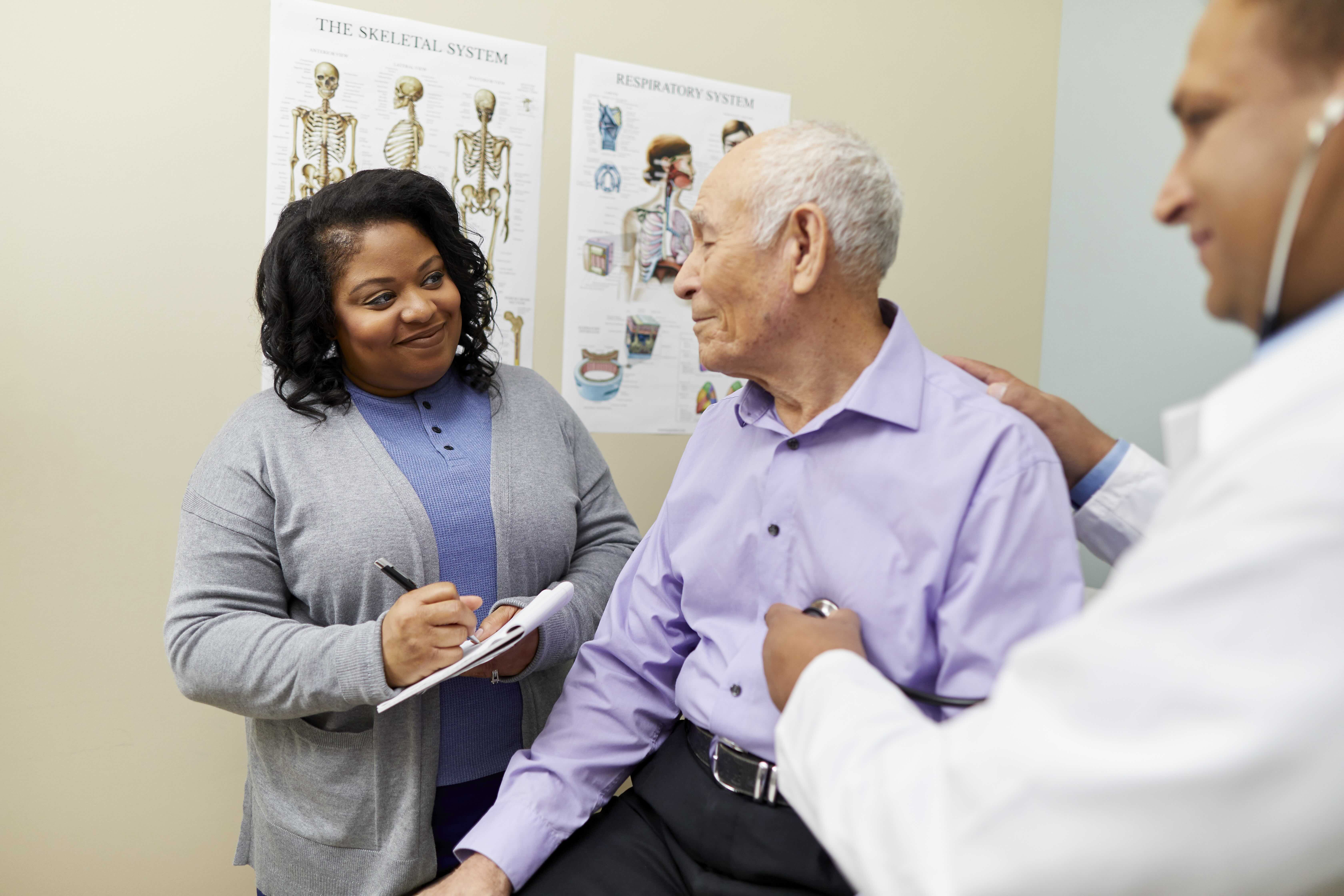 Senior male patient being attended to by a nurse and physician in a clinic setting.