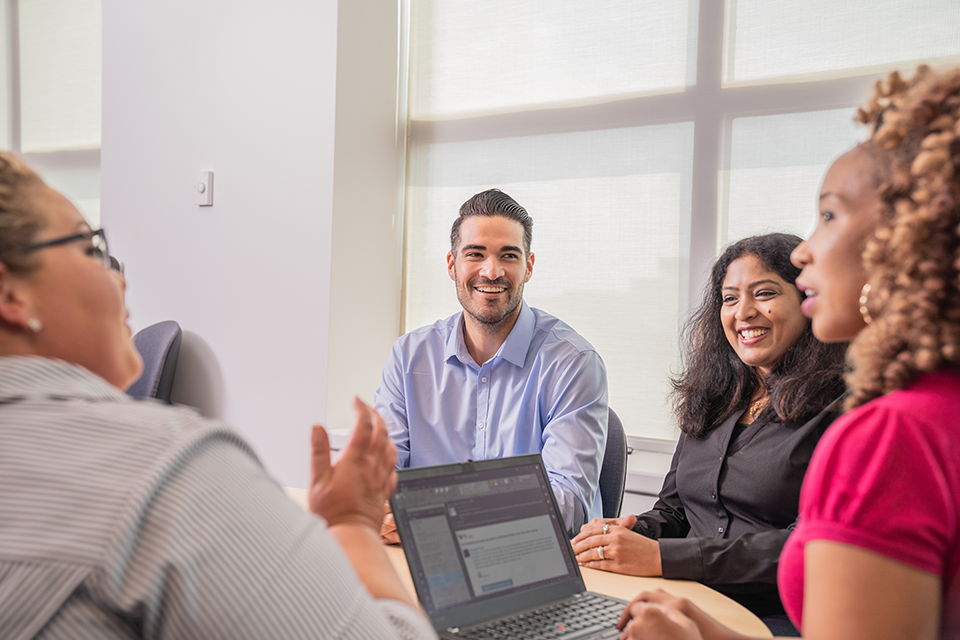 A team of professionals sitting at a table working and smiling